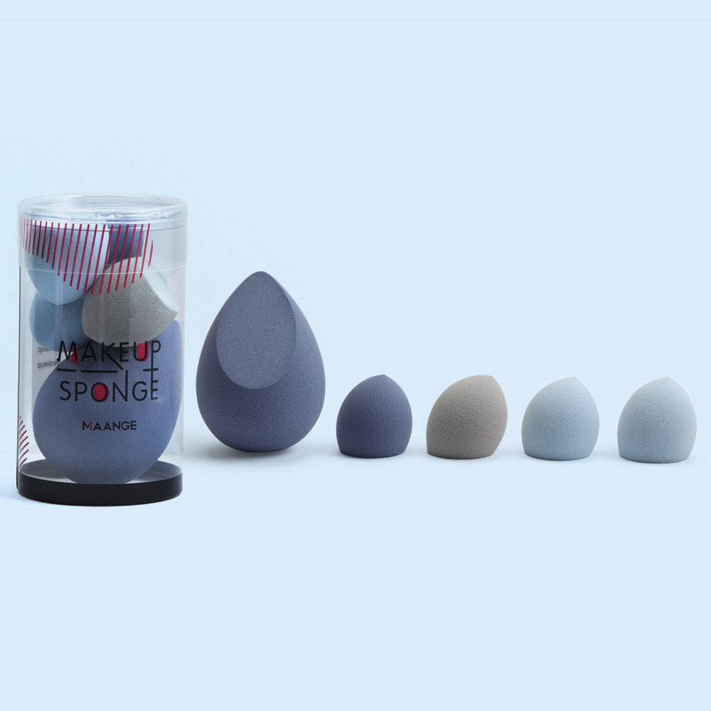 Assorted blue and grey teardrop-shaped makeup sponges in a clear container and lined up.