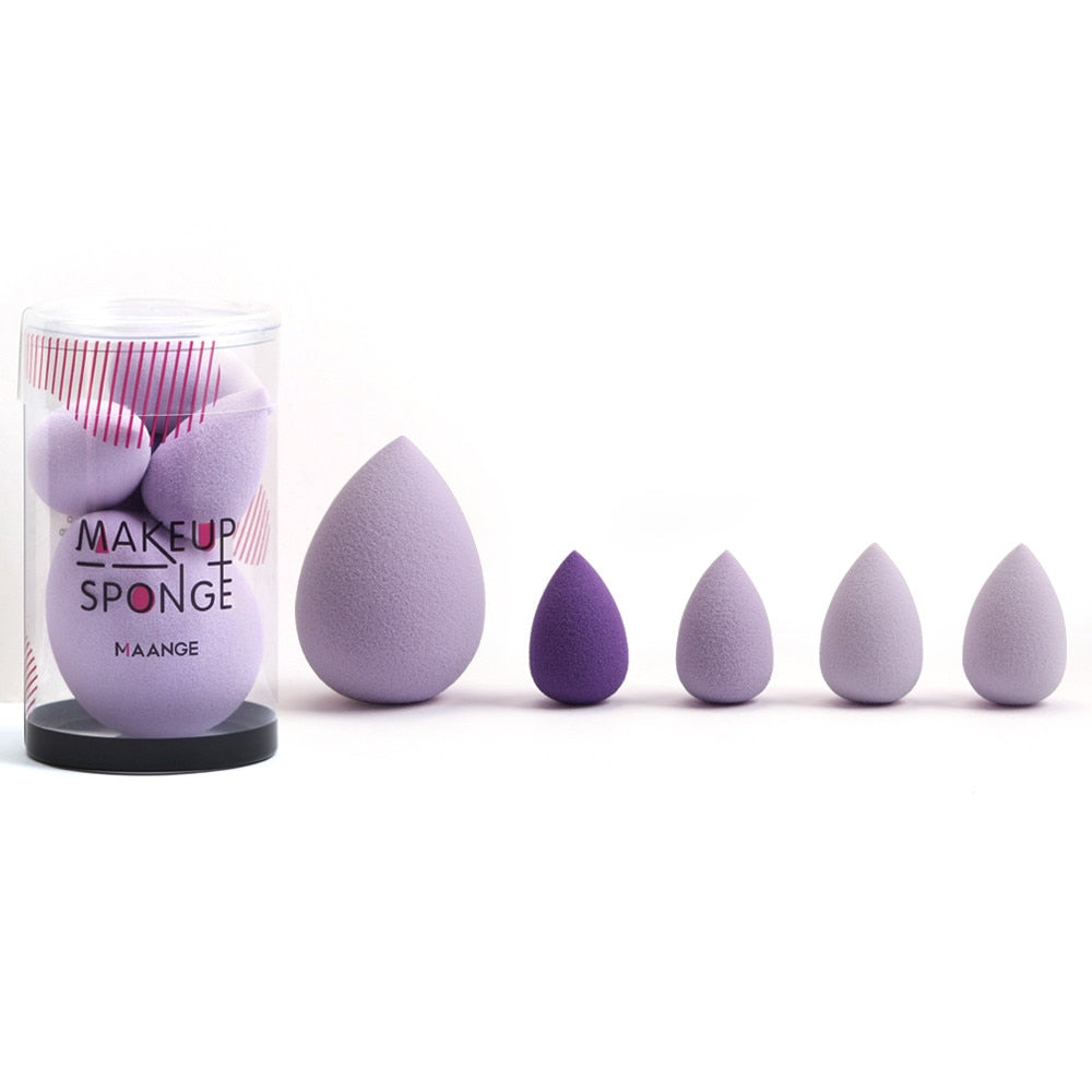 Set of purple teardrop-shaped makeup sponges in a clear container and arranged by size.