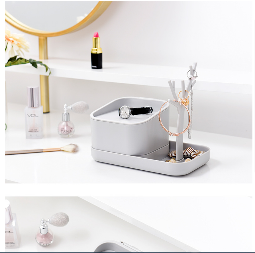 Modern grey jewelry organizer tray with watch, rings, and bracelets on a white vanity