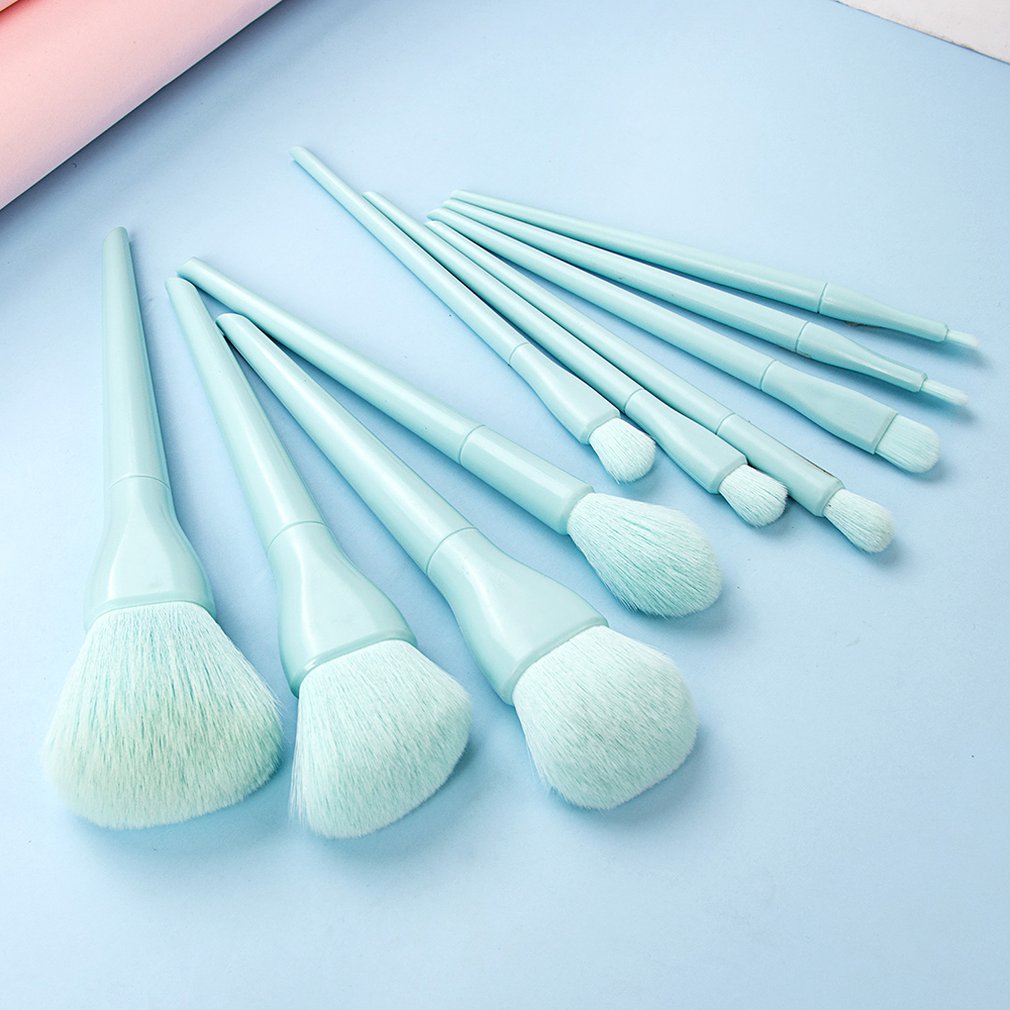 Set of light blue makeup brushes of various sizes on a blue background