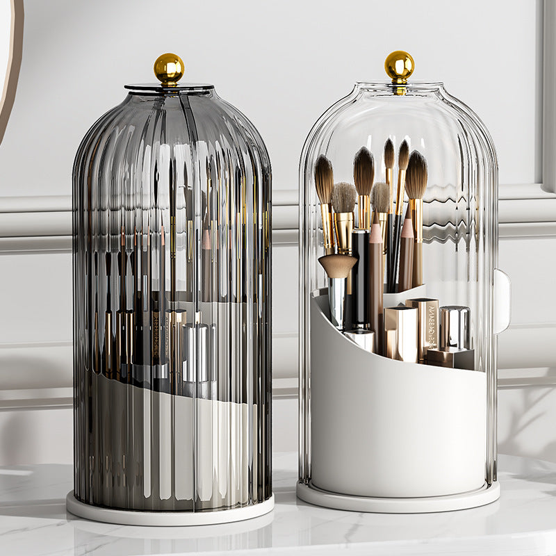 Two elegant glass cloche makeup organizers with gold finials holding cosmetic brushes and products.