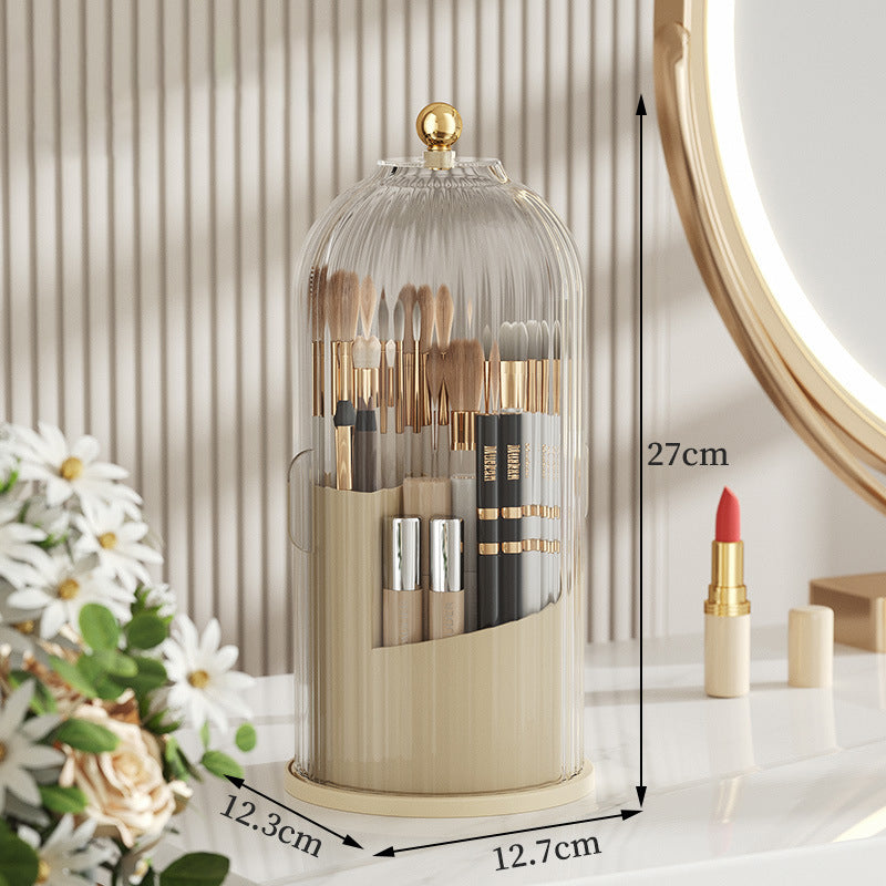 Clear glass makeup brush holder with gold accents and dome lid on a white vanity